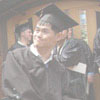 A graduate looks on as another talks with a faculty member during Commencement lineup in the Foss Center.